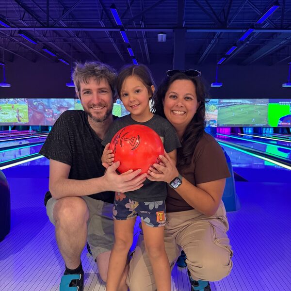 Taylor, her husband, and their daughter at a bowling alley.